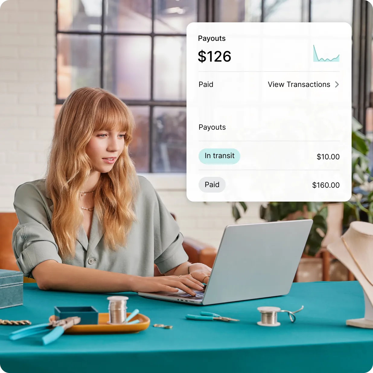 White female PlatformDTC merchant works on her laptop to set up PlatformDTC Payments for her jewelry business