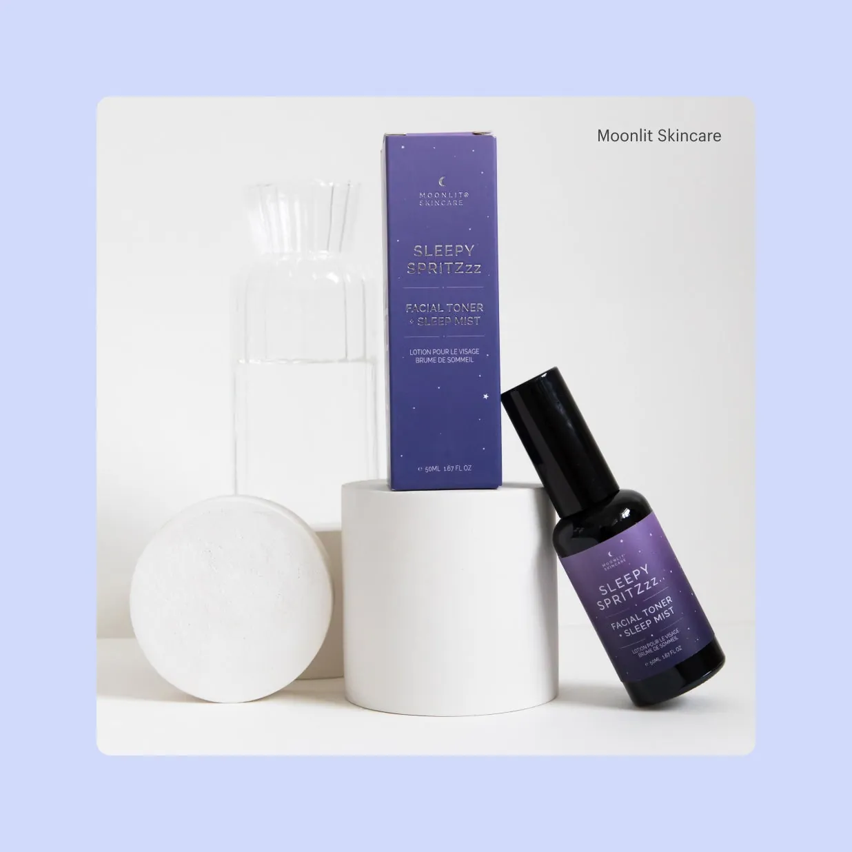 A product display featuring purple package for Moonlit Skincare’s Sleepy Spritzzz.. facial toner, and a small spray bottle of Sleepy Spritzzz.. facial toner