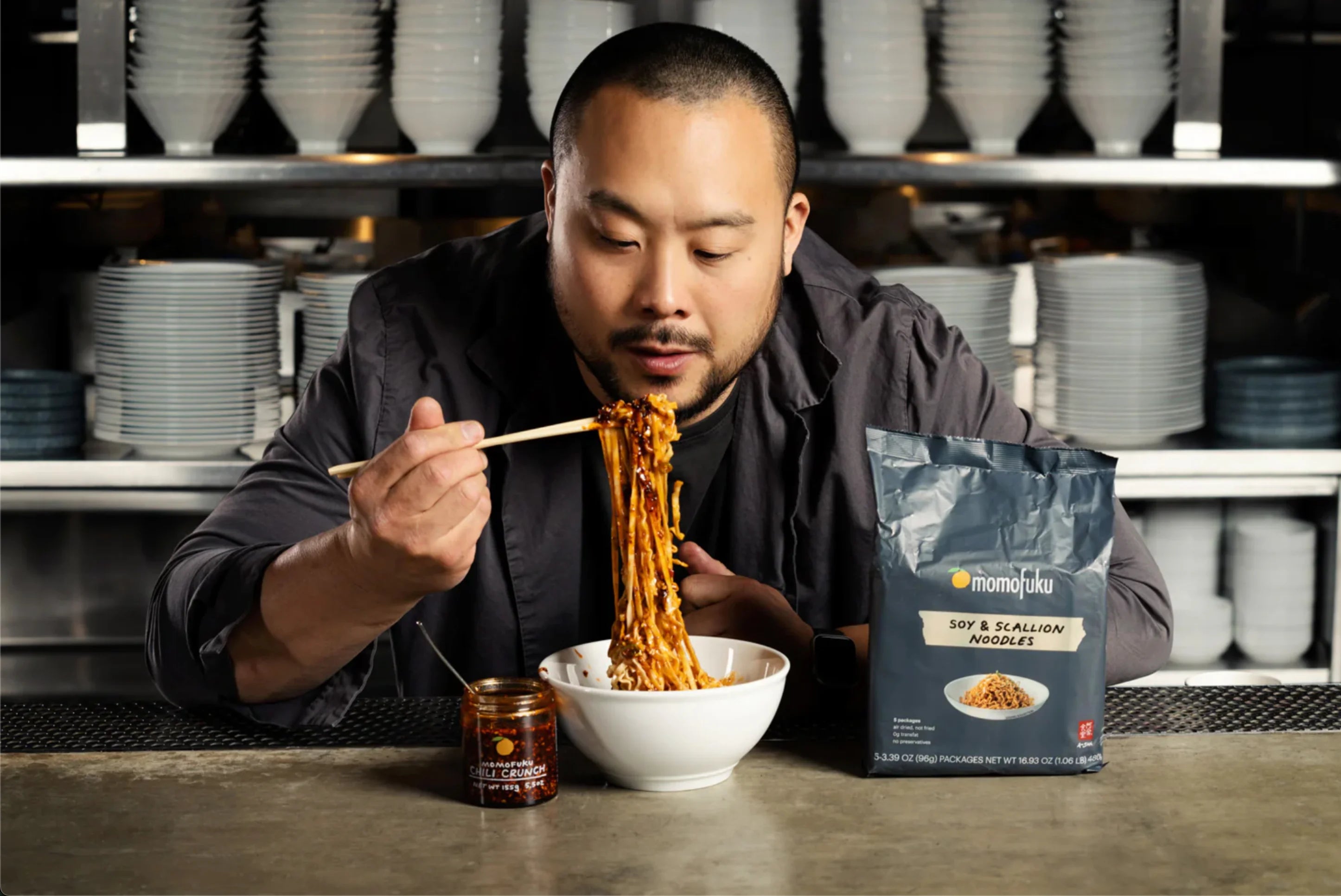 A card highlighting PlatformDTC merchant Momofuku, featuring David Chang (owner of Momofuku) eating a bowl of noodles.